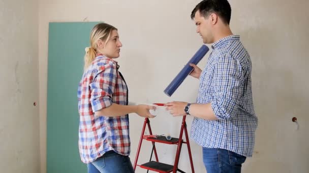 4k cuplikan pasangan yang tersenyum bahagia memilih wallpaper untuk apartemen baru mereka yang sedang direnovasi — Stok Video