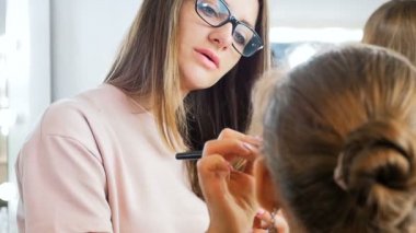 Visage stüdyoda model ile çalışan profesyonel makyaj sanatçısı Closeup yavaş hareket video. Fırça ile kozmetik uygulayan kadın