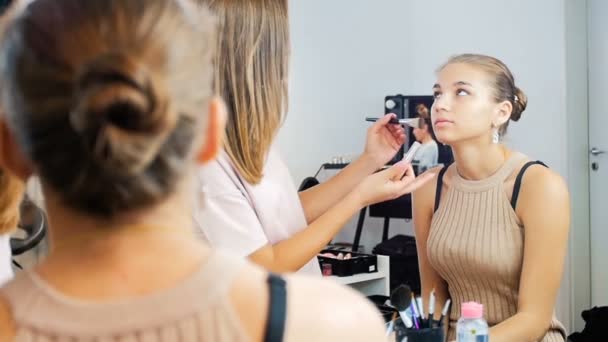 Primer plano de imágenes en cámara lenta de artista de maquillaje profesional aplicando maquillaje en la cara modelos antes de desfile de moda — Vídeo de stock