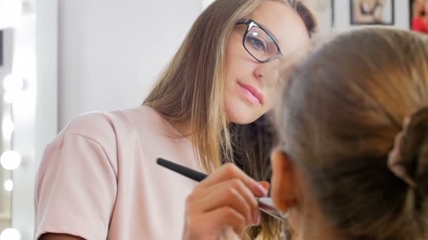 Closeup lassú mozgás videó professzionális sminkes alkalmazása kozmetikumok és előkészítése a fiatal női modell photoshooting — Stock videók