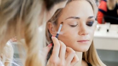 Visage stüdyoda model ile çalışan profesyonel makyaj sanatçısı Closeup yavaş hareket video. Fırça ile kozmetik uygulayan kadın