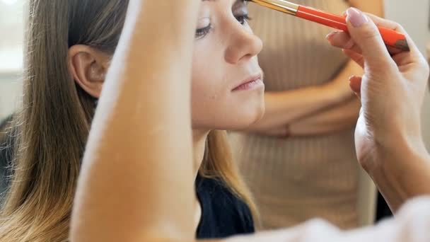 Primer plano video en cámara lenta de artista de maquillaje profesional pintando ojos y aplicando rímel. Visagiste preparando el modelo para el desfile de moda o sesión de fotos. Mujer que usa rímel y otros cosméticos — Vídeo de stock