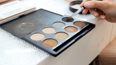 Makyaj için boya lar ve gölgeler ile renkli palet Closeup video. Profesyonel makyaj sanatçısı veya visagiste tutma paleti ve fırça ile doğru renk toplama