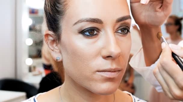 Nahaufnahme Zeitlupe Video von professionellen Make-up-Artist Anwendung Kosmetik und Vorbereitung junge weibliche Modell für Fotoshooting — Stockvideo