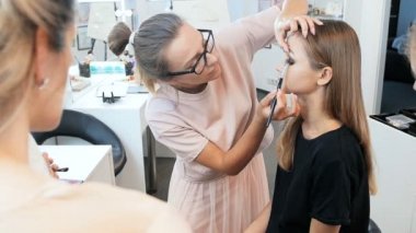 Kadın profesyonel makyaj sanatçısının, öğrencilerine maskara, ruj ve tonları uygulayarak modellere yüz lerini öğrettiği video. Profesyonel visage sınıf alan genç kadın