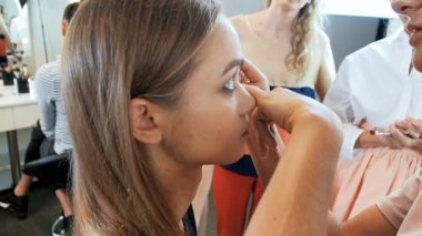 Kozmetik uygulayan ve fotoçekim için genç kadın modeli hazırlanıyor profesyonel makyaj sanatçısı Closeup yavaş hareket video