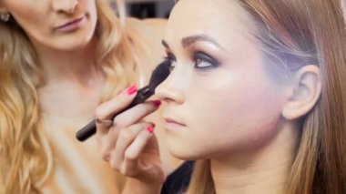 Kozmetik uygulayan ve fotoçekim için genç kadın modeli hazırlanıyor profesyonel makyaj sanatçısı Closeup yavaş hareket video