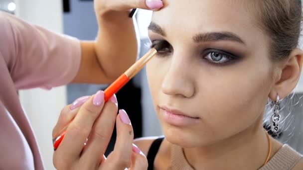 Closeup slow motion video of professional makeup artist painting eyes and applying mascara. Visagiste preparing model for the fashion show or photoshooting. Woman using mascara and other cosmetics — Stock Video