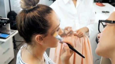 Profesyonel makyaj stüdyosunda modelleri yüz makyaj uygulayarak kadın visagiste Closeup yavaş hareket video