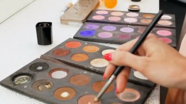 Makyaj için boya lar ve gölgeler ile renkli palet Closeup video. Profesyonel makyaj sanatçısı veya visagiste tutma paleti ve fırça ile doğru renk toplama
