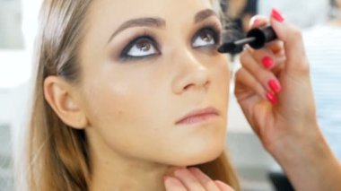 Visage stüdyoda model ile çalışan profesyonel makyaj sanatçısı Closeup yavaş hareket video. Fırça ile kozmetik uygulayan kadın