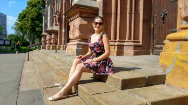 Kasaba nın caddesindeki eski taş merdivenlerde oturan kısa elbiseli güzel genç kadın