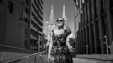 Modern bina ve antik katedraller ile sokakta yürüyen güneş gözlüğü gülümseyen genç kadın siyah beyaz görüntü