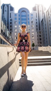 Kısa elbise ve güneş ışınları taş merdiven üzerinde poz güneş gözlüğü güzel seksi genç kadın Portresi