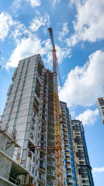 Image of high building crane on construction site of new modern district against blue sky with white clouds — Stock Photo, Image