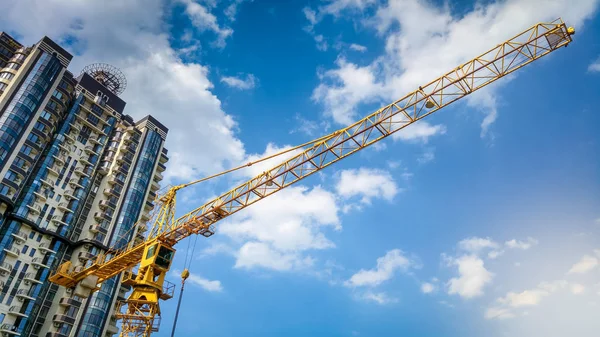 Imagem de guindaste de edifício alto no local de construção contra o céu azul e arranha-céus — Fotografia de Stock