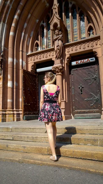 Beautiful young woman in short dress posing on old stone stairs at cathotilc cathedral — Stock Photo, Image