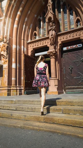 Beautiful young woman in short dress standing on old stone stairs at catholic cathedral at european town — Stock Photo, Image