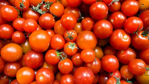 Macro image of lots of red small cherry tomatoes on counter at vegetable store. Texture or pattern of fresh ripe vegetables — Stock Photo, Image