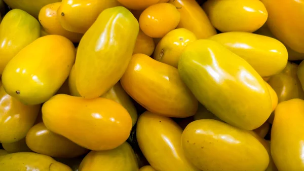 Nahaufnahme Bild von vielen gelben langen Tomaten im Lebensmittelgeschäft. Textur oder Muster von frischem reifem Gemüse — Stockfoto