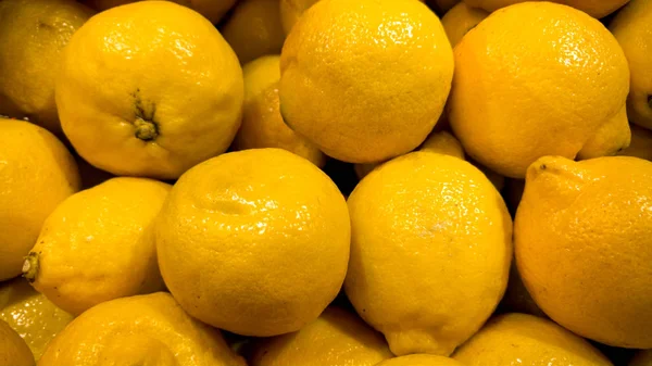 Foto de cerca de un montón de limones amarillos. Textura de primer plano o patrón de frutas frescas maduras. Hermoso fondo de comida — Foto de Stock