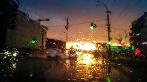 Zbliżenie obraz kropelek na mokrej przedniej szyby samochodu w deszczu na światło zachodu słońca. Streszczenie strzał mokrej szyby w promieniach słońca — Zdjęcie stockowe