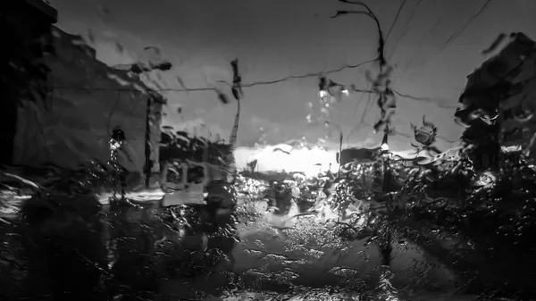 雨时水滴在汽车挡风玻璃上流动的黑白图像。湿汽车挡风玻璃 — 图库照片
