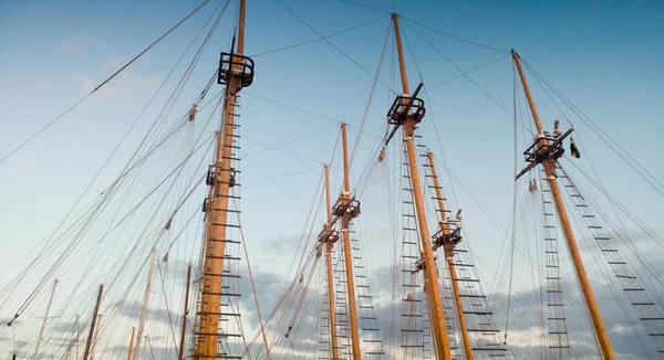 Image of high wooden masts of old ships in port against blue sky at evening — Stock Photo, Image