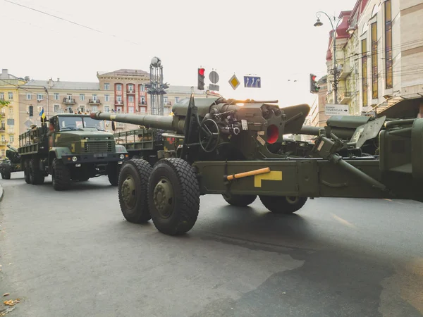 Тонированное изображение большой пушки и военных грузовиков, едущих по городской улице во время военного парада — стоковое фото