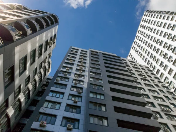 Mavi gökyüzü ve parlak güneşe karşı modern çok mağazalı yaşam binasının çatılarında yerden görünümü
