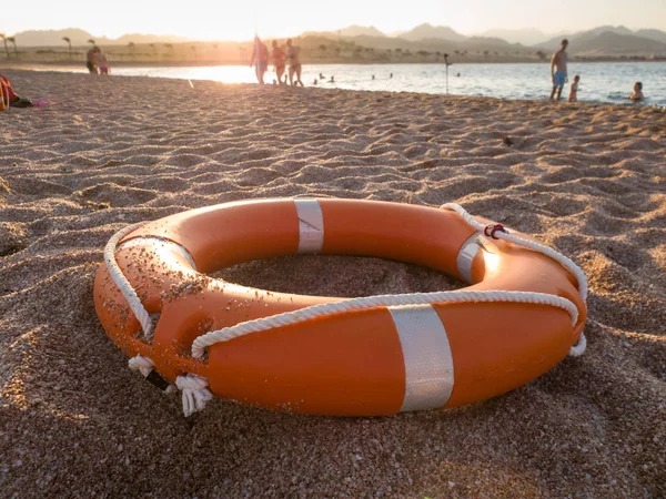 Imagen de primer plano del anillo salvavidas de plástico rojo en la playa de arena al atardecer —  Fotos de Stock