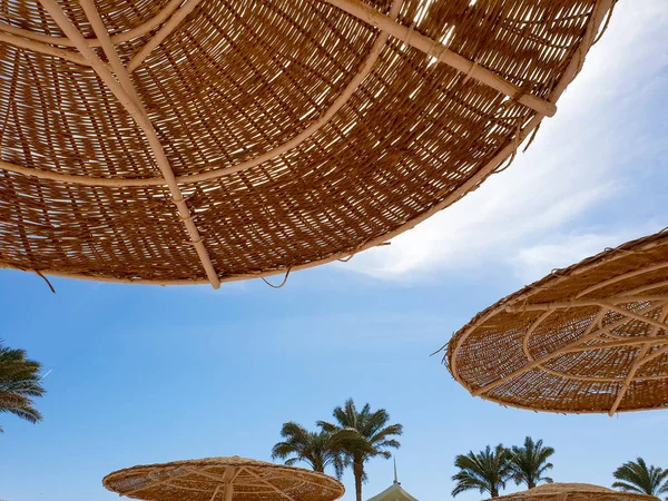 Photo de parasols en paille protégeant du soleil sur la plage contre le ciel bleu vif — Photo