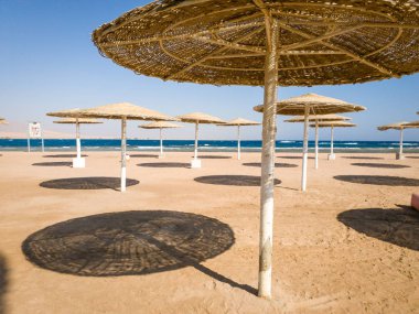 Mavi gökyüzüne karşı sıcak güneşli bir günde okyanus sahilinde saman şemsiye görüntü