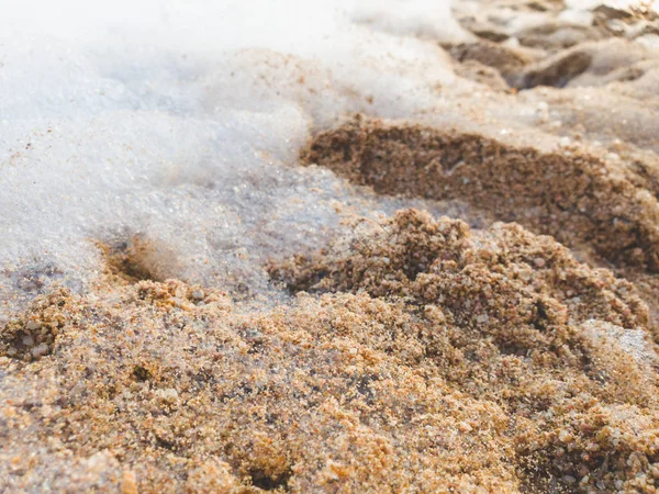 Immagine ravvicinata di schiuma e cumuli sulla spiaggia di sabbia in mare. Sfondo astratto . — Foto Stock