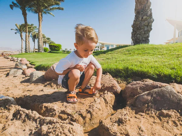 Kumlu plajda oturan sevimli yürümeye başlayan çocuk tonda görüntü ve ıslak kumdan kale bina — Stok fotoğraf