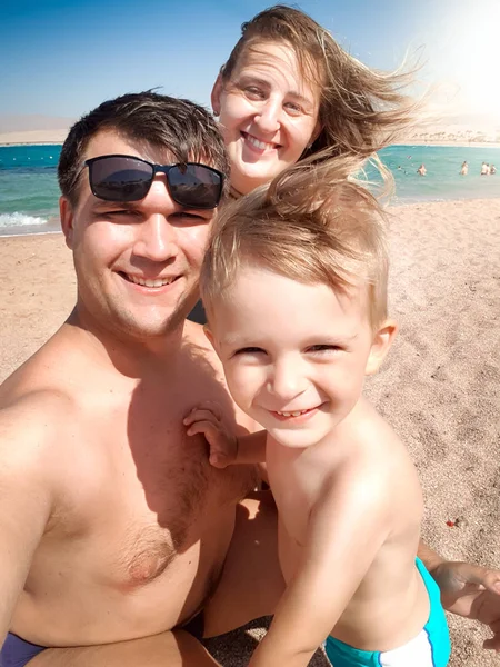 Selfie portrait of happy smiling cheerful family on the sea beach at sunny windy day. Family relaxing and having good time during summer holiday vacation. — Stock Photo, Image