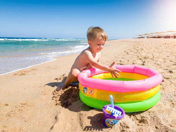 3 lata stary godny podziwu chłopiec gra na plaży morskiej z nadmuchiwanym basenem. Dziecko relaksujące i dobrze się bawią podczas letnich wakacji. — Zdjęcie stockowe
