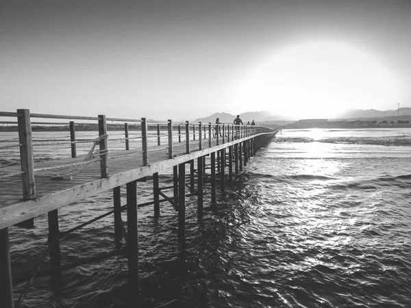 太阳在海浪和长木码头上落山的画面 — 图库照片