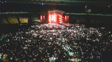 Rock müzik konserinde hayranlarıyla dolu büyük stadyumun defocused fotoğrafı. Parti, disko veya müzik festivalini göstermek için mükemmel bir zemin
