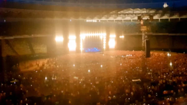 Foto borrosa abstracta de gran multitud en el concierto de rocas en el estadio por la noche. Fondo perfecto para ilustrar fiestas, discotecas o festivales de música —  Fotos de Stock