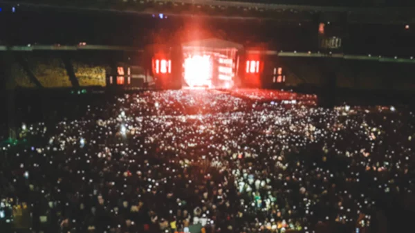 ロックコンサートでファンでいっぱいの大きなスタジアムのデフォーカス写真。パーティー、ディスコ、音楽フェスティバルを描く完璧な背景 — ストック写真
