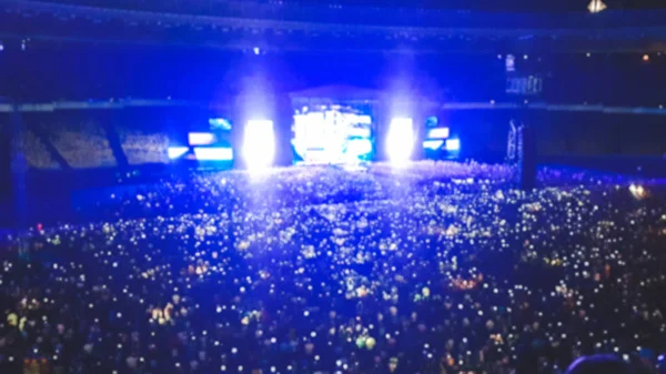 Foto borrosa abstracta de gran multitud en el concierto de rocas en el estadio por la noche. Fondo perfecto para ilustrar fiestas, discotecas o festivales de música —  Fotos de Stock