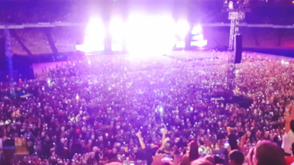 Foto borrosa abstracta de gran multitud en el concierto de rocas en el estadio por la noche. Fondo perfecto para ilustrar fiestas, discotecas o festivales de música — Foto de Stock