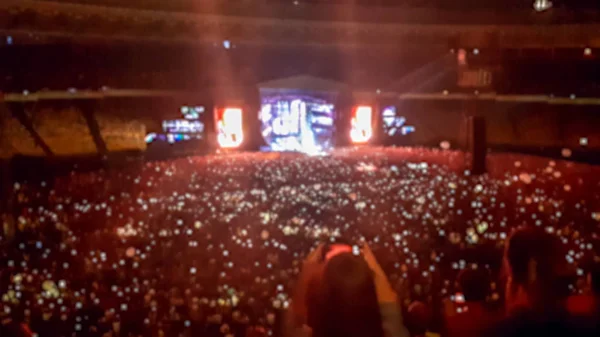 Foto borrosa abstracta de gran multitud en el concierto de rocas en el estadio por la noche. Fondo perfecto para ilustrar fiestas, discotecas o festivales de música — Foto de Stock