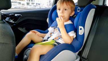 Sevimli yürümeye başlayan çocuk çocuk çocuk güvenlik koltuğunda oturan ve çerezleri yeme Portresi