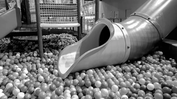 Schwarz-Weiß-Bild der Rutsche auf dem Kinderspielplatz mit vielen bunten Plastikbällen im Freizeitpark — Stockfoto