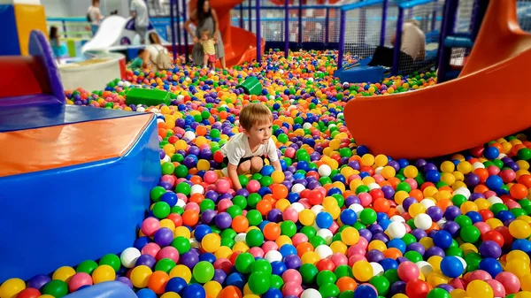 Foto de un niño jugando en la piscina llena de bolas de plástico colroful. Niño divirtiéndose en el parque infantil en el centro comercial — Foto de Stock