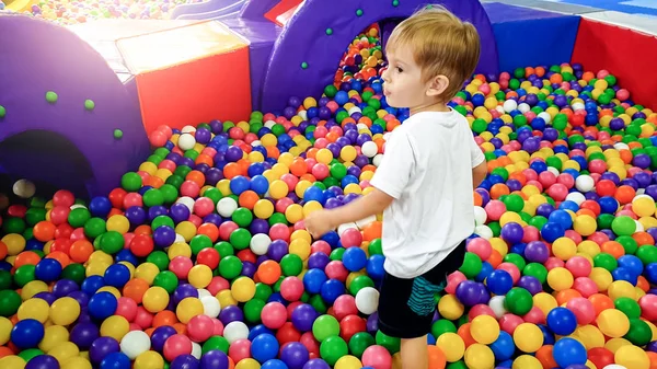 Image of 3 years old toddler boy playing and having fun on the playground with lots of small colorful plastc ball. Child enjoying amusement park in the shopping mall — Stock Photo, Image