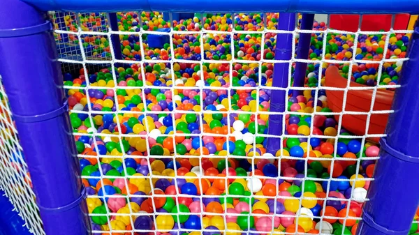 Zbliżenie obraz duży basen pełen kolorowych plastikowych kulek na placu zabaw dla dzieci ogrodzony z siatką dla dzieci bezpieczeństwa — Zdjęcie stockowe