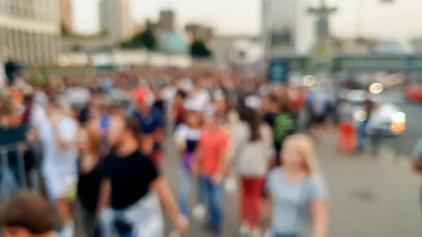 Out of focus image of big crowd of people walking on the city street